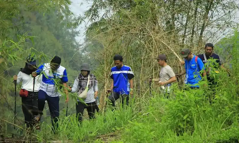 Sekelompok peserta trekking berjalan di jalur alam hijau sebagai aktivitas pendukung gathering di Villa Bukit Pancawati Bogor.