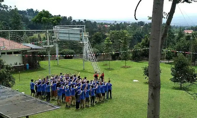 Peserta outbound berkumpul di lapangan dengan latar area high rope dan pemandangan hijau di Villa Bukit Pancawati Bogor.