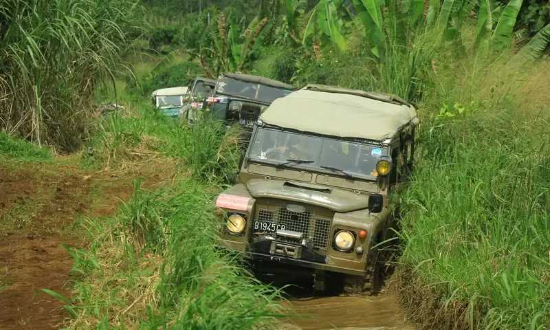 Konvoi mobil Land Rover offroad melewati jalur tanah berlumpur di Puncak Bogor sebagai bagian dari paket gathering muatan outbound plus offroad.