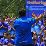 Instruktur BoundEx Indonesia berbaju biru sedang memandu ratusan peserta gathering perusahaan di Bogor dalam sesi pembukaan outbound yang inspiratif dan penuh semangat.