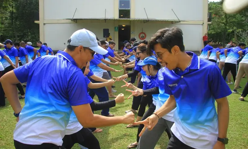 Peserta gathering perusahaan sedang melakukan permainan kompetisi Suit Samurai dalam kegiatan outbound di Bogor. Tampak interaksi seru antar karyawan berbaju biru yang saling berhadapan di lapangan terbuka untuk meningkatkan energi dan keakraban kelompok.