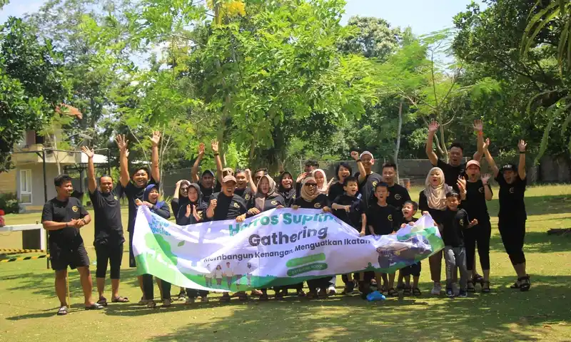 Peserta korporat berfoto bersama membawa banner BoundEx saat mengikuti paket family gathering di Bogor dengan latar belakang taman hijau yang asri.