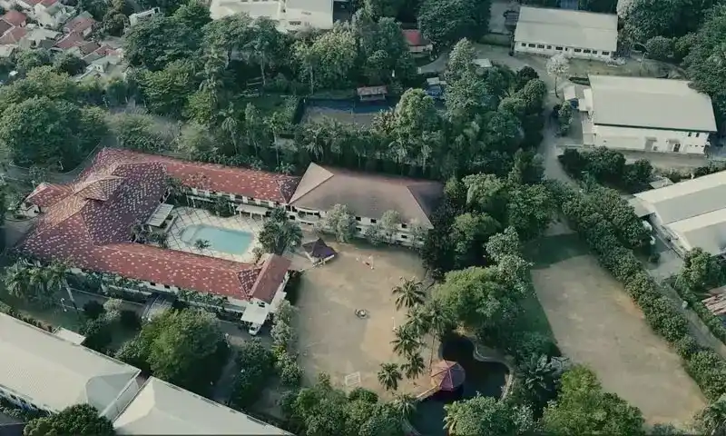 Pemandangan udara Ole Suite Hotel & Cottage Sentul, Bogor. Terlihat bangunan cottage beratap merah yang mengelilingi kolam renang biru, lapangan terbuka luas untuk aktivitas outbound, dan rimbunnya pepohonan hijau di sekitar lokasi tempat family gathering di Bogor.