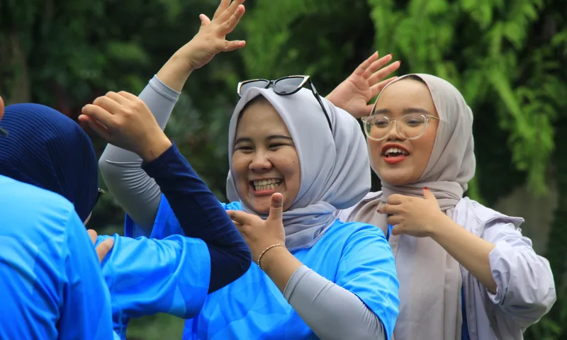 Peserta gathering perusahaan tersenyum dan berinteraksi dalam sesi fun games outdoor.