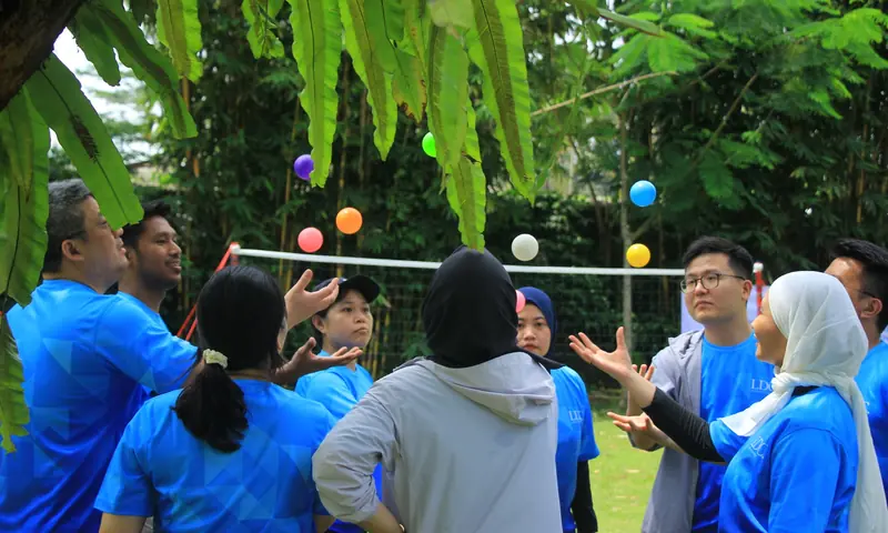 Peserta outbound kantor mengikuti fun games komunikasi dengan bola warna-warni