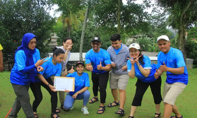 Kelompok peserta team building berpose bersama setelah menyelesaikan tugas kelompok di area outdoor.
