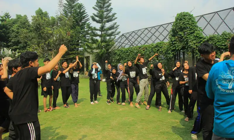 Peserta perusahaan mengikuti low impact games outbound Puncak di area rumput terbuka.