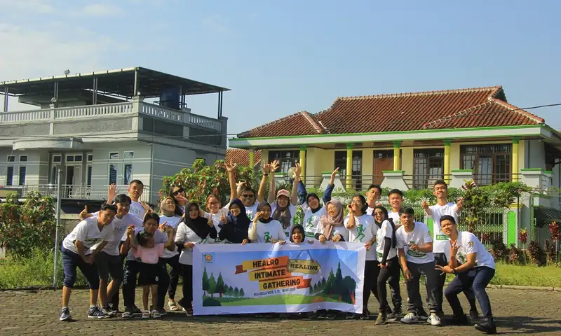 Peserta outing perusahaan berfoto bersama banner gathering di area villa Puncak Bogor.
