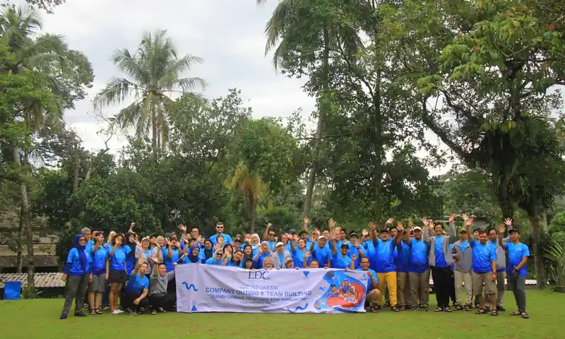 Peserta perusahaan berfoto bersama setelah kegiatan outbound Puncak 2D1N dengan banner team building.