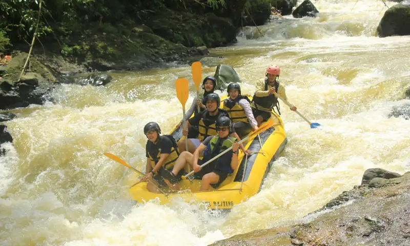 Peserta kantor mengikuti aktivitas rafting dengan perlengkapan helm dan pelampung sebagai bagian dari paket outbound plus rafting Bogor.