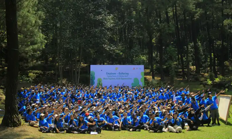 Peserta gathering perusahaan berkaus biru berfoto bersama di area hutan pinus Gunung Pancar Sentul
