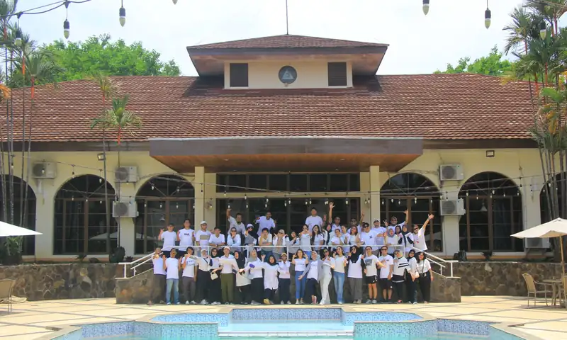 Peserta gathering perusahaan berfoto di depan bangunan dan area kolam Olè! Suites Hotel & Cottage Sentul.