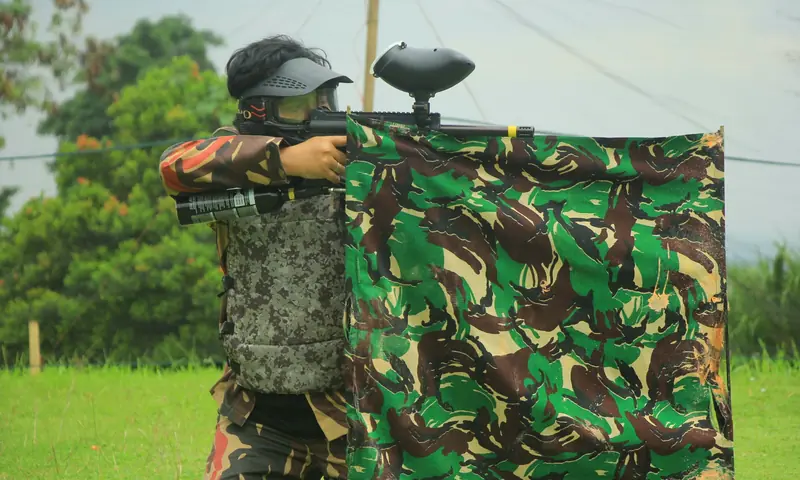 Peserta outbound perusahaan mengikuti simulasi paintball di Bogor dengan perlengkapan pelindung lengkap di area outdoor.