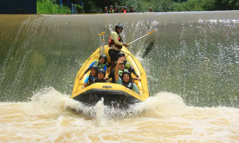 Tim peserta outbound perusahaan menuruni arus sungai menggunakan perahu rafting di Bogor sebagai aktivitas kelompok.
