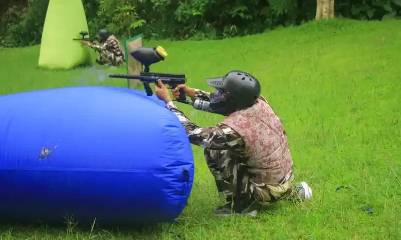 Peserta outbound Pancawati bermain paintball di lapangan rumput dengan perlengkapan pelindung