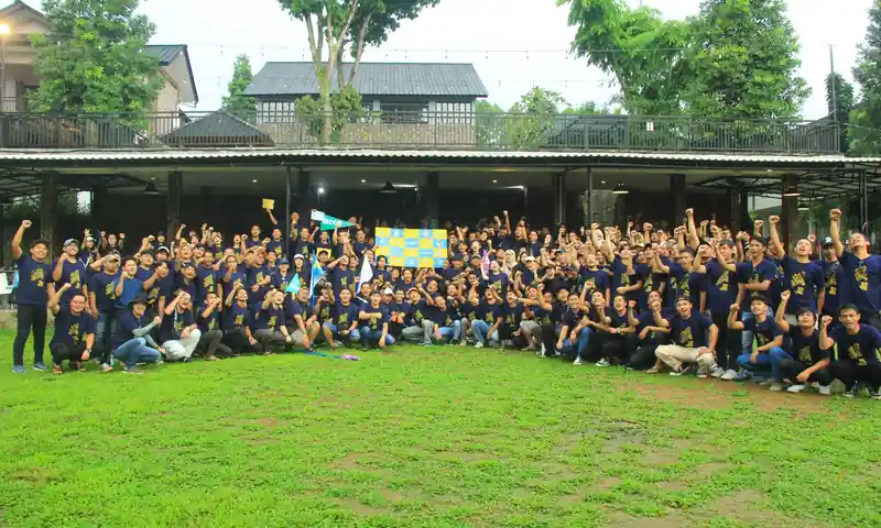 Rombongan besar peserta outing perusahaan berfoto bersama di lapangan hijau Bogor