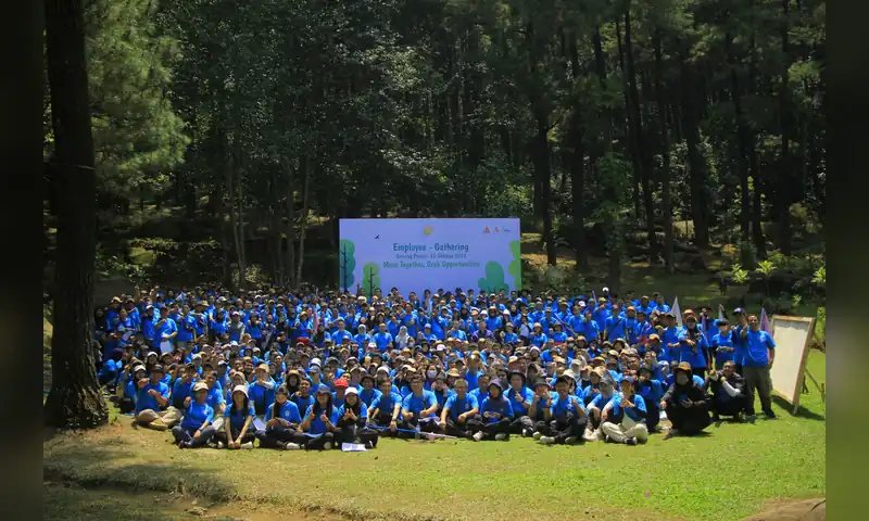Grup besar peserta gathering perusahaan di Bogor berfoto bersama di area hutan pinus.