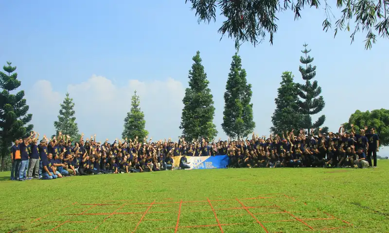 Foto grup peserta gathering perusahaan di lapangan Pondok Kapilih Pancawati saat sesi kebersamaan outdoor.