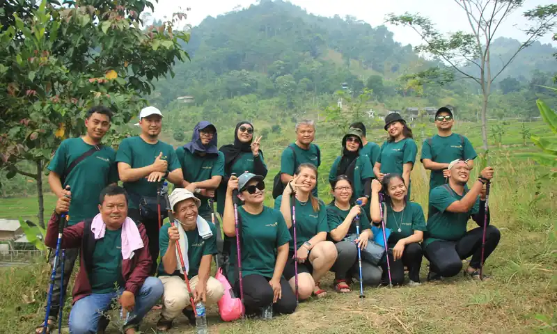Kelompok peserta gathering perusahaan berfoto bersama di area perbukitan setelah aktivitas trekking.