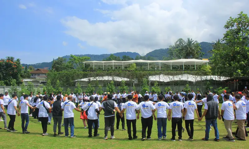 Peserta gathering perusahaan mengikuti aktivitas outbound di lapangan Teras Bhumi Puncak Bogor dengan latar pegunungan