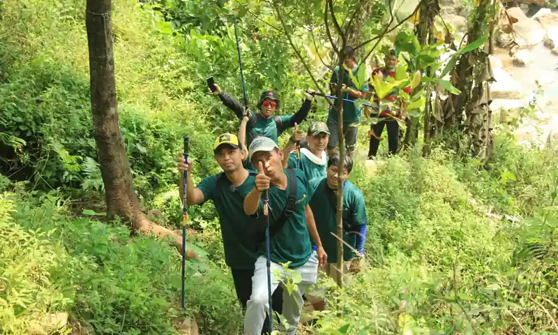 Peserta trekking berjalan di jalur hijau sebagai aktivitas tambahan gathering perusahaan di kawasan Sentul